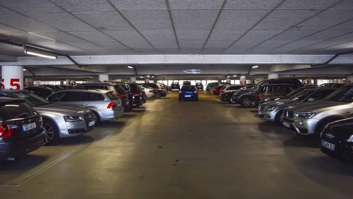 Un garaje lleno de coches, con un coche azul en el centro. Los gastos de compra de garaje son altos.