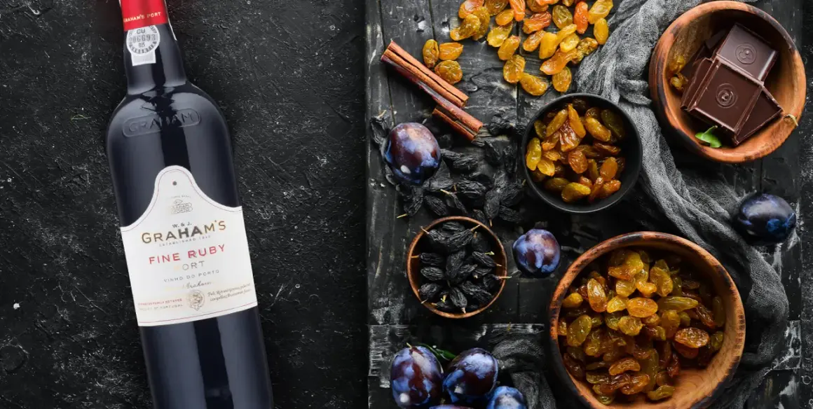 Butelka Graham's Fine Ruby Port obok bakalii: rodzynek, śliwek, czekolady i cynamonu. Idealny do deserów, porto ile procent?