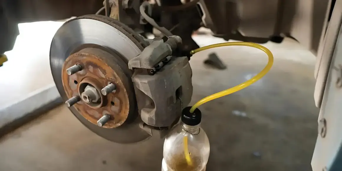 Proceso de purgar frenos: un tubo amarillo conecta la pinza de freno a una botella para extraer el líquido.