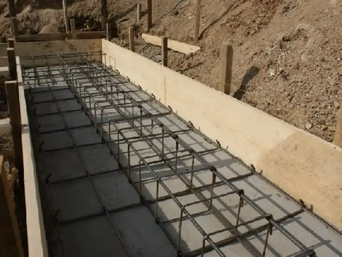 Siatka zbrojeniowa w drewnianej formie, gotowa na betonowanie. Widać, ile zbrojenia na fundamenty potrzeba do solidnej konstrukcji.