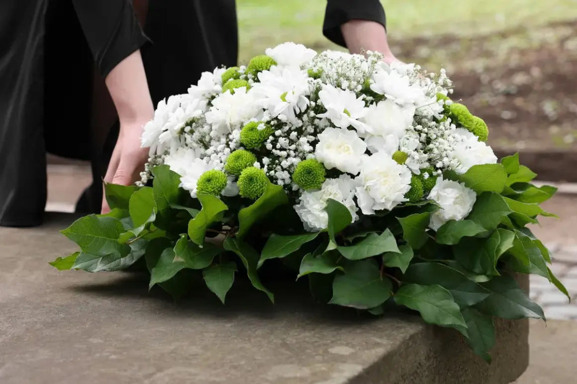 Piękne dekoracje z chryzantem na Wszystkich Świętych, ułożone z troską na kamiennym postumencie.