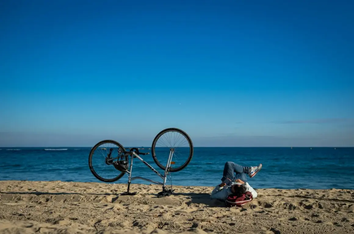 Odpoczynek po przejażdżce Velo Baltica. Rower na plaży, człowiek leży na piasku, patrząc na morze.
