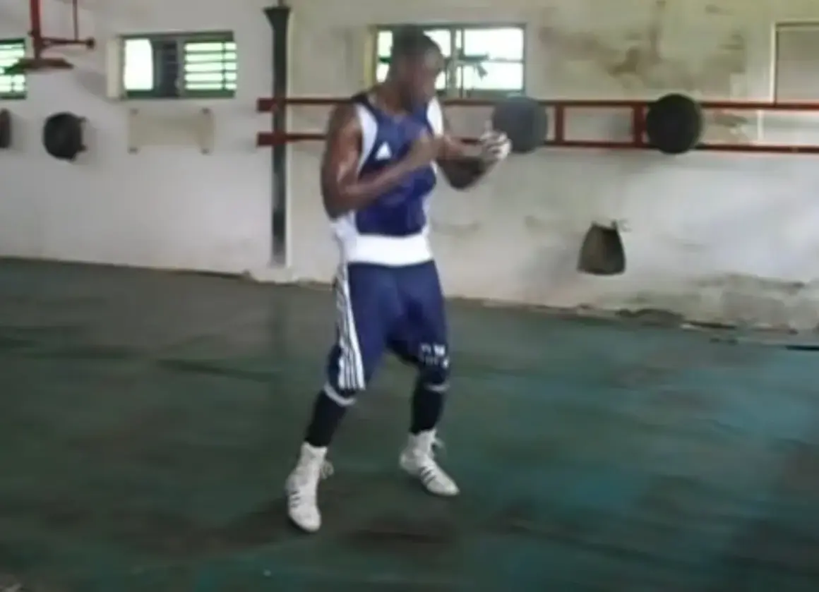 A boxer trains in a sparse gym, practicing his moves with a determined look. The scene evokes a sense of dedication, reminiscent of soviet style boxing.
