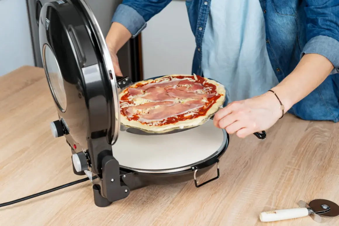 Osoba wkłada pizzę z szynką do pieca. Szybko i łatwo przygotujesz idealne danie.