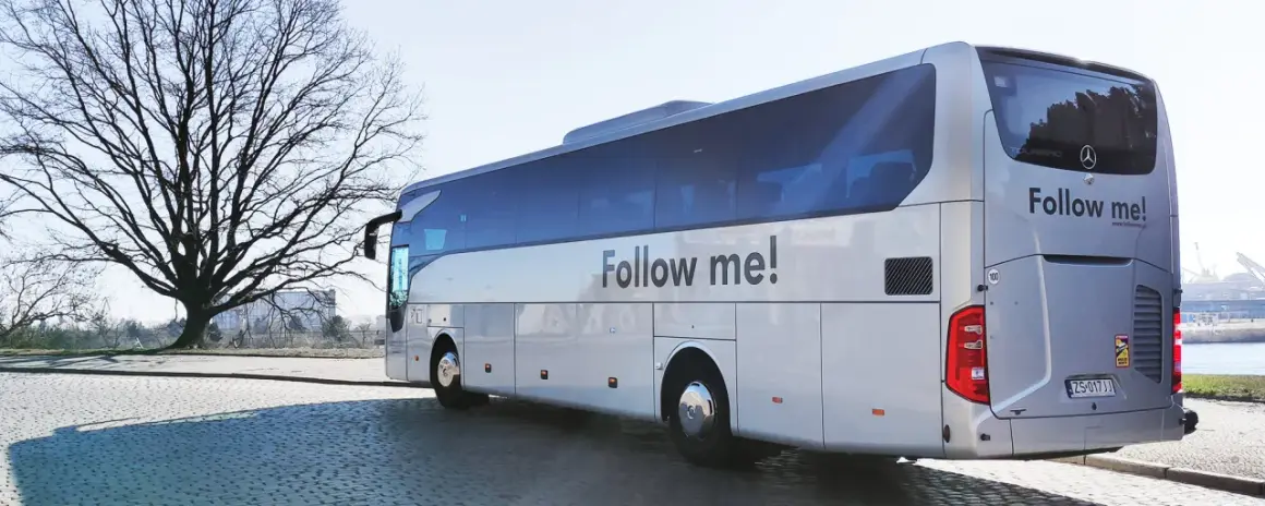 Autokar z napisem "Follow me!" czeka na pasażerów przy lotnisku w Koszalinie.