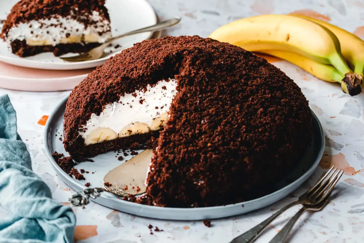 Ein saftiger veganer Maulwurfkuchen mit Bananen und Sahne, bedeckt mit Schokoladenkrümeln.