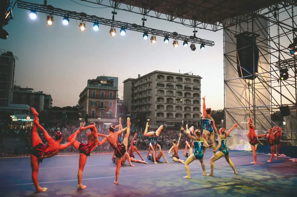 Atleti in posa sul palco di Riccione, un'esibizione di ginnastica ritmica che incanta il pubblico.