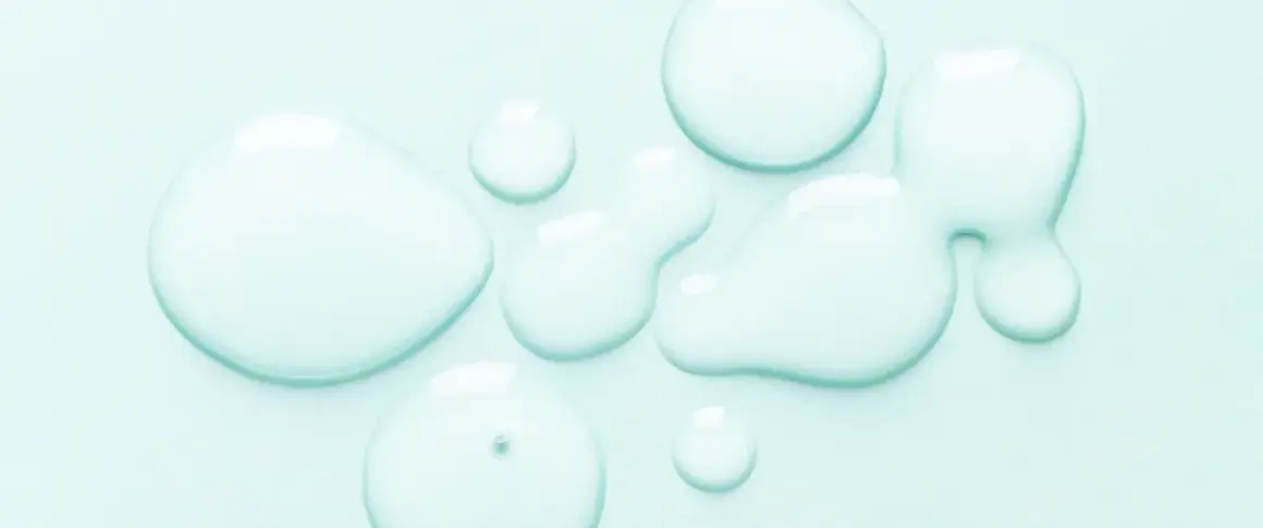 Gocce trasparenti su sfondo azzurro. Alcuni si chiedono se il cocamidopropyl betaine fa male, ma questa immagine mostra solo liquidi puri.