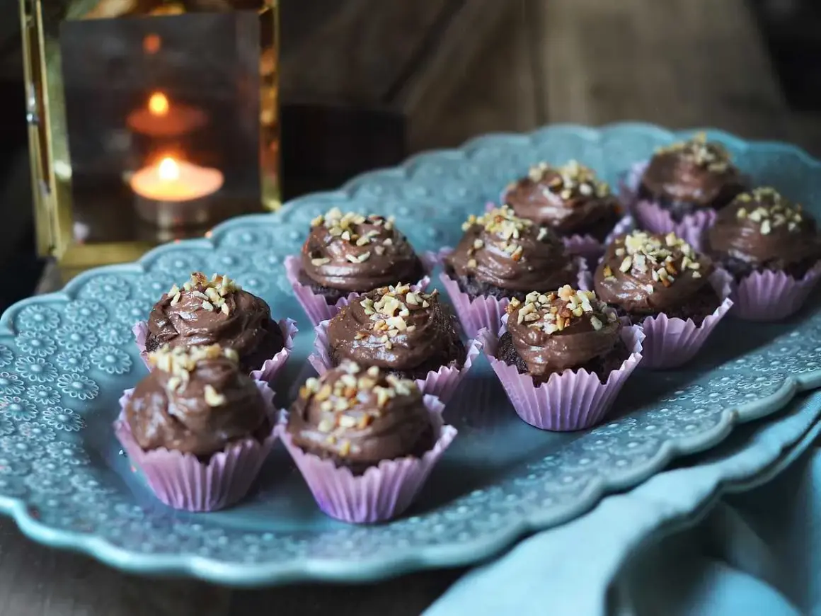Mini cupcakes choklad med krämig frosting och hackade nötter, serverade på ett vackert fat.