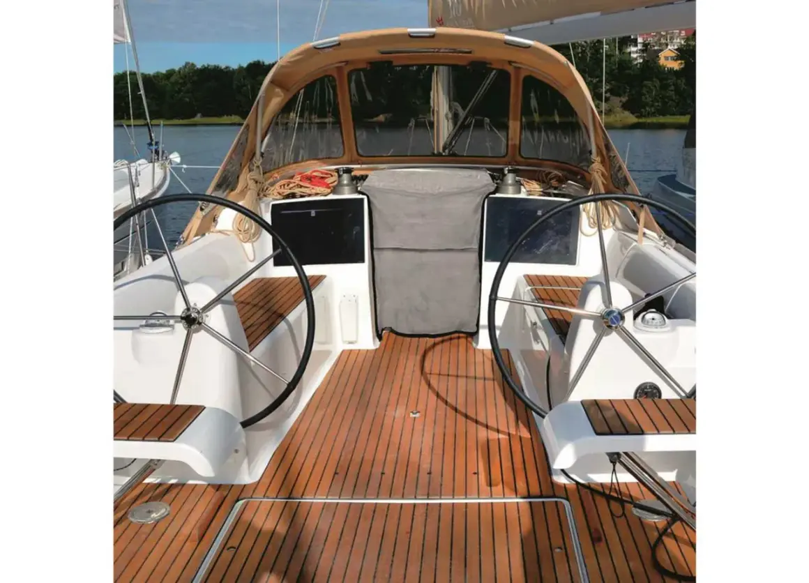 Il ponte di uno yacht con due timoni, un tendalino e un boccaporto, pronto per la navigazione.