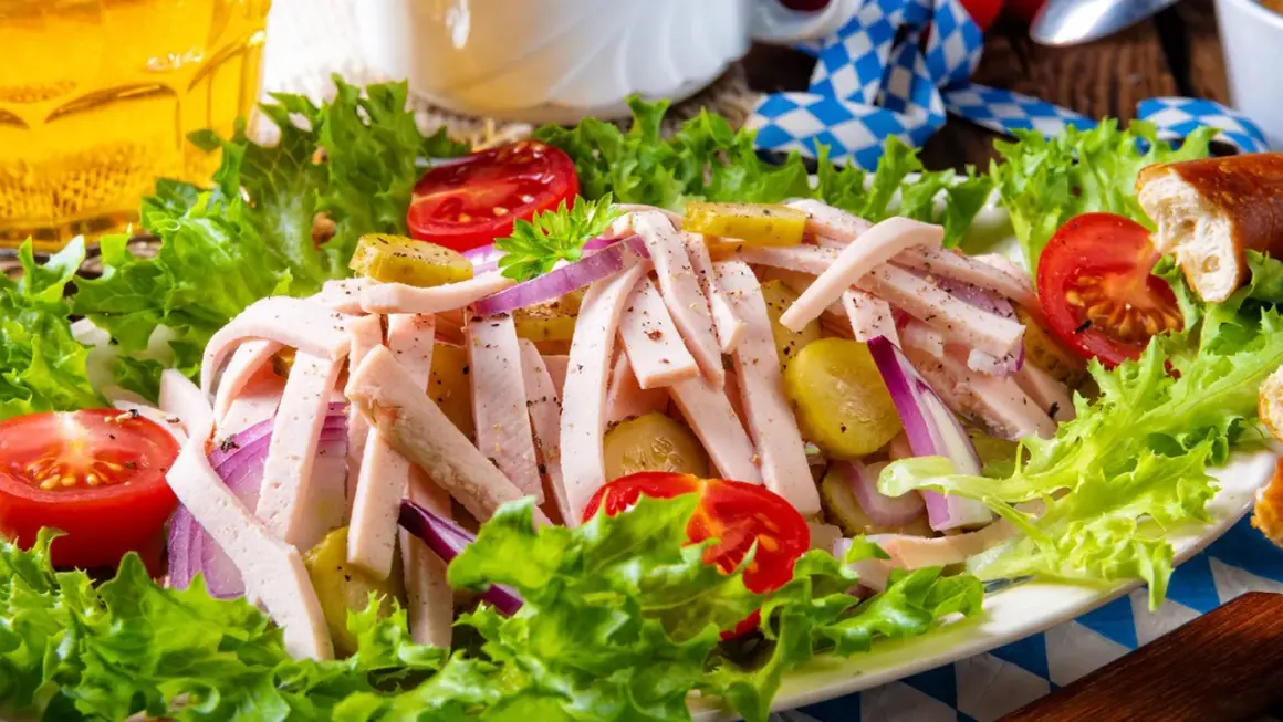 Ein leckerer Wurstsalat mit Tomaten, Gurken und Zwiebeln, perfekt für ein deftiges wurstsalat rezept. Dazu ein Glas Bier.
