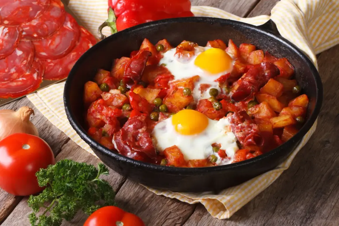 Pyszny obiad z jajek z ziemniakami, chorizo i groszkiem w patelni.