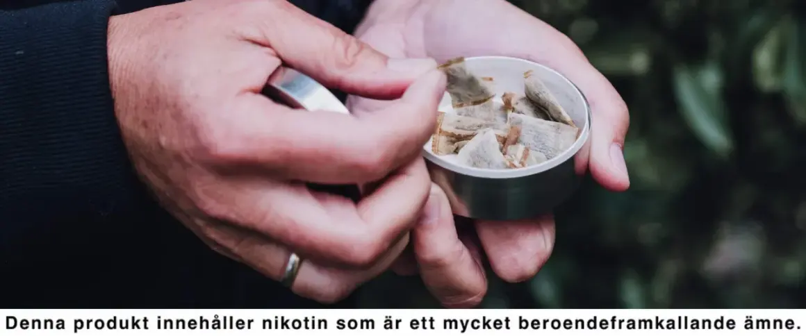 Händer tar en prilla snus ur en dosa. En perfekt dag för snusets dag, men kom ihåg nikotinets beroendeframkallande natur.