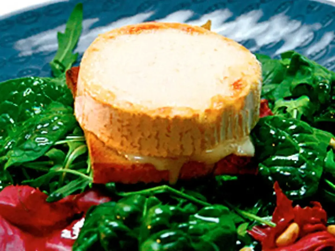Varm chevre chaud på rostat bröd, serverad med en fräsch sallad av spenat och ruccola. Smältande ost och gröna blad.