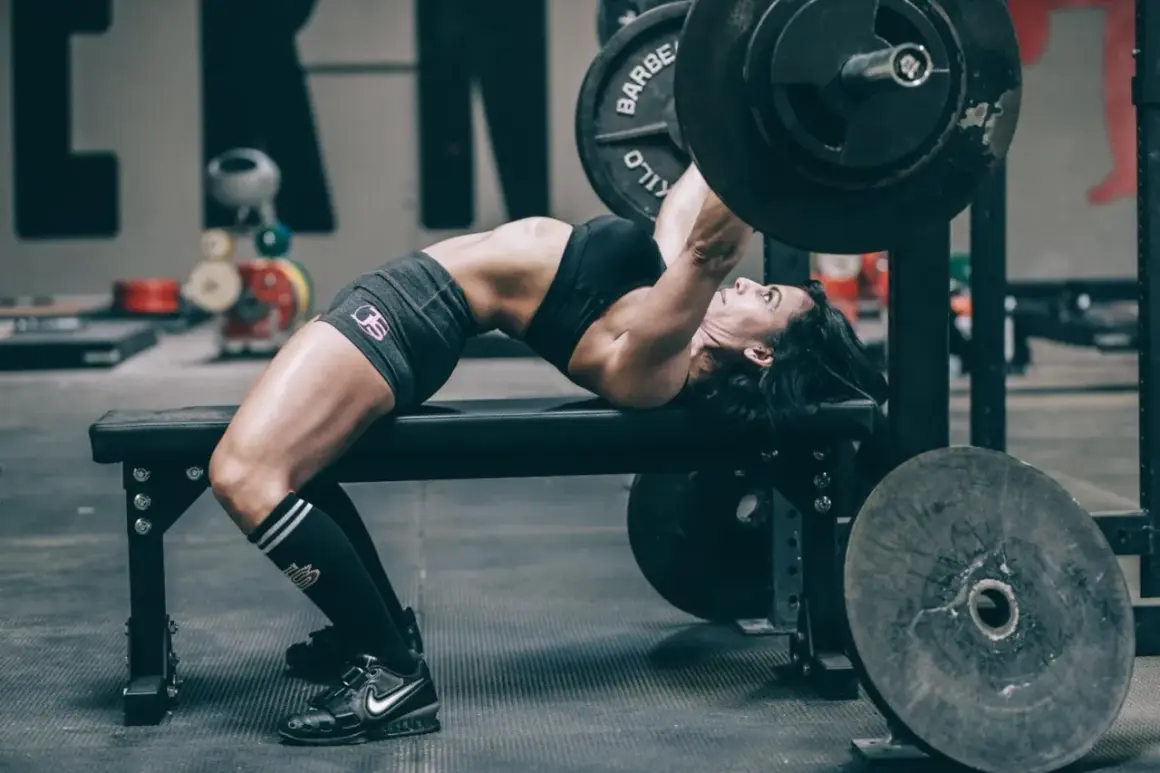 Frau hebt mit starkem Rücken und angespannten Muskeln eine Hantel im Rahmen des German Volume Training.