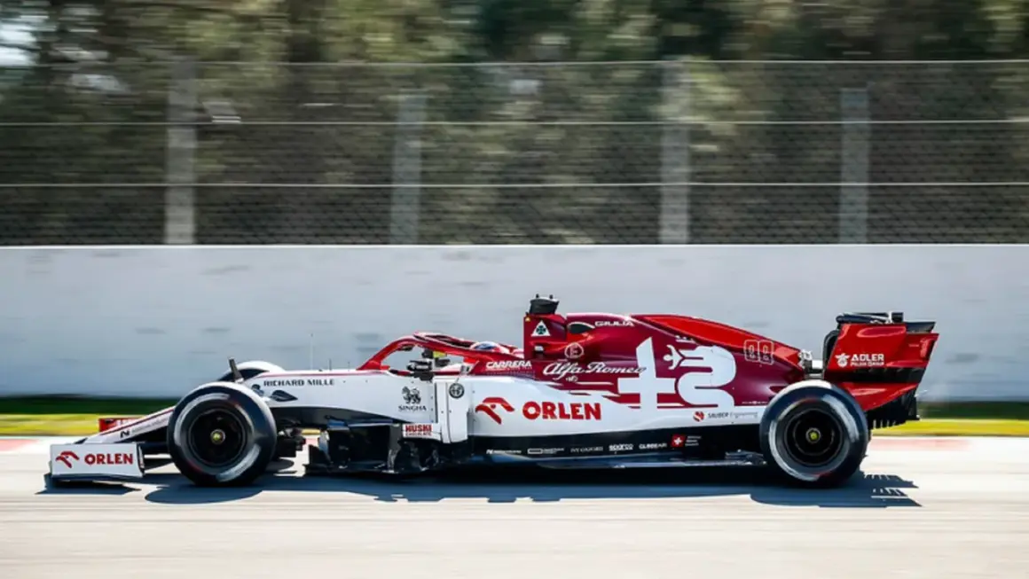 Biało-czerwony bolid Alfa Romeo F1 z numerem 7 pędzi po torze.