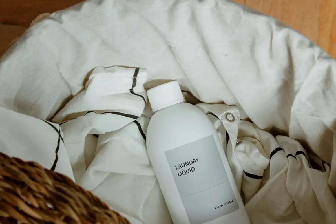 Una botella de líquido para la colada descansa entre la ropa blanca, lista para que el lino se dé de sí.