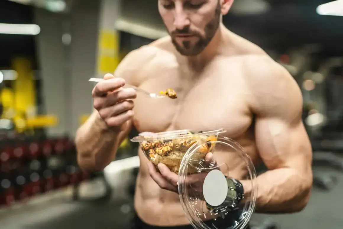 Un homme musclé mange un repas sain dans une salle de sport. Il utilise des protéines végétales pour sa musculation.
