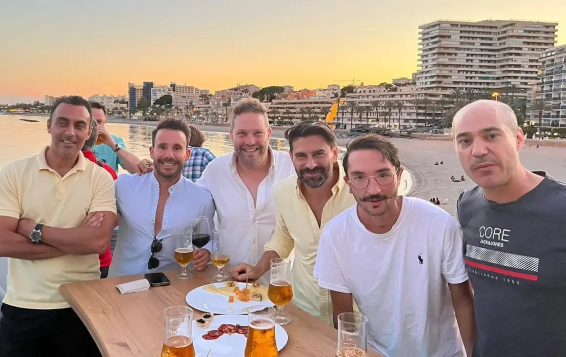 Amigos brindan en el puerto de Aguadulce de noche, con el mar y edificios de fondo.