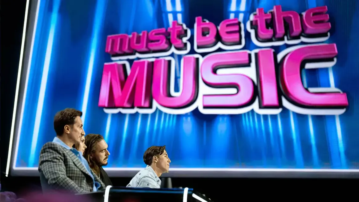 Trzech jurorów siedzi przed ekranem z napisem "must be the MUSIC".