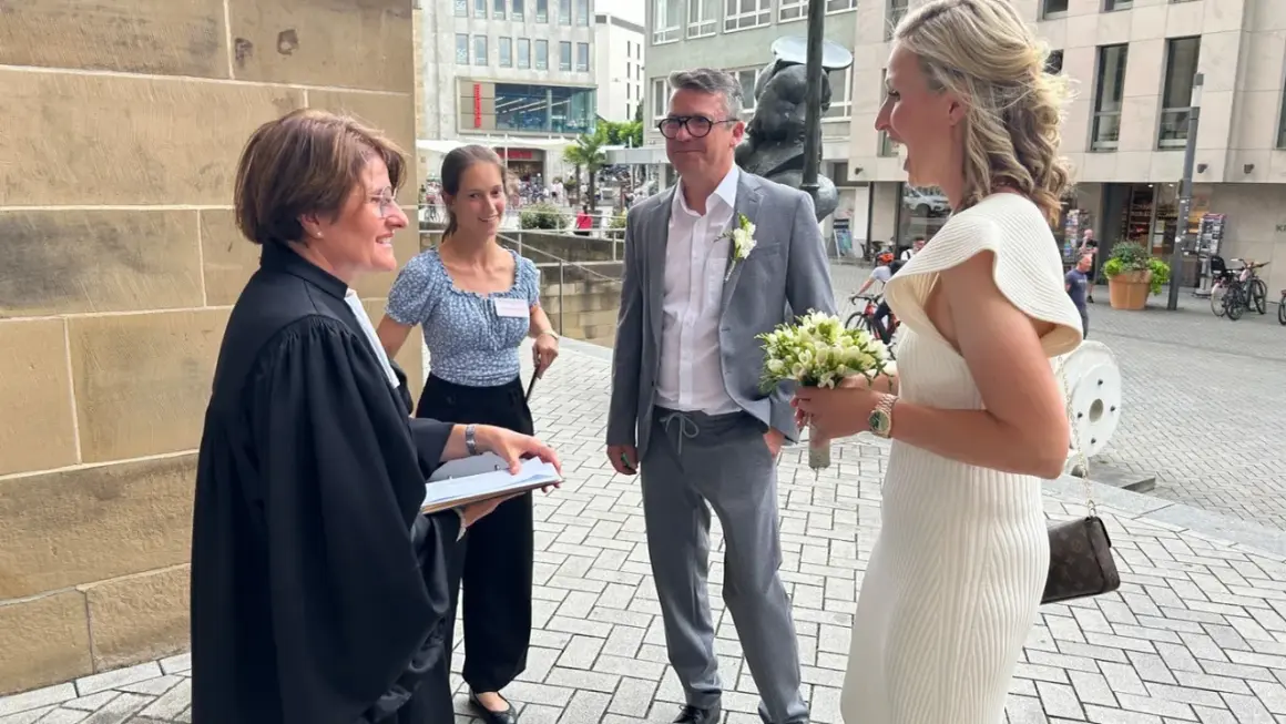 Hochzeitsmesse Heilbronn: Ein Paar feiert seine Hochzeit mit einem Blumenstrauß vor einer Kirche.