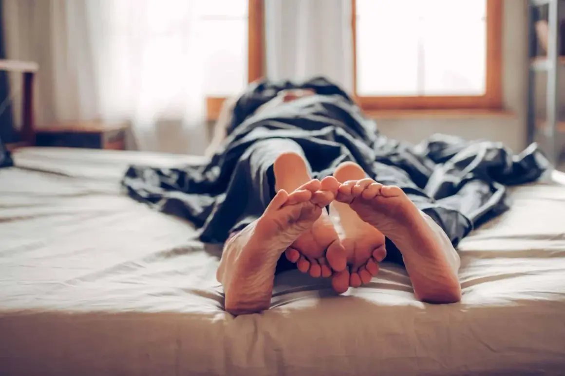 Zwei Füße berühren sich unter einer Decke. Ein Paar, das sich an die Regel "kein Sex vor der Ehe" hält, genießt die Nähe.