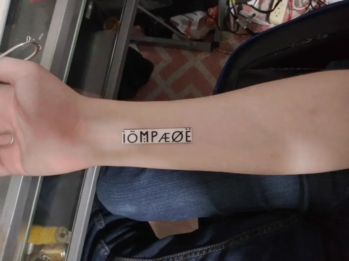 Nowy tatuaż na przedramieniu: ÌÕMPÆØË. Wygląda jak tajemniczy symbol.