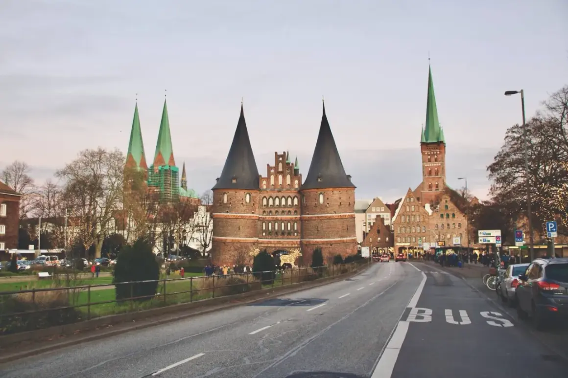 Holstentor, en ikonisk portbyggnad i norra Tyskland, med sina karaktäristiska torn och kyrkor i bakgrunden.