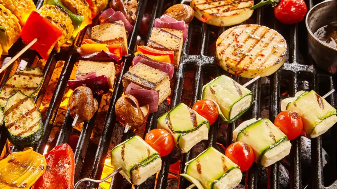 Bunte Spieße mit Tofu, Zucchini, Tomaten, Mais und Paprika brutzeln auf dem Grill. Ein Genuss für vegetarisches Grillen!