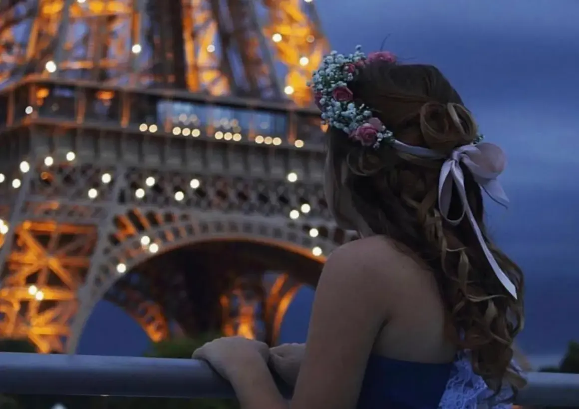 Ragazza con coroncina di fiori guarda la Torre Eiffel illuminata, un'atmosfera romantica perfetta per idee proposta di matrimonio.