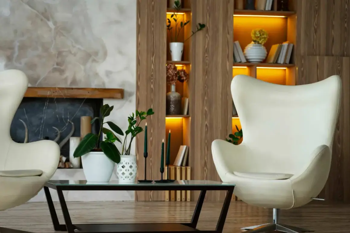 Gemütliches Wohnzimmer mit zwei weißen Eier-Sesseln, einem Couchtisch mit Pflanzen und Kerzen, Kamin und einem Regal im **mid century design**.