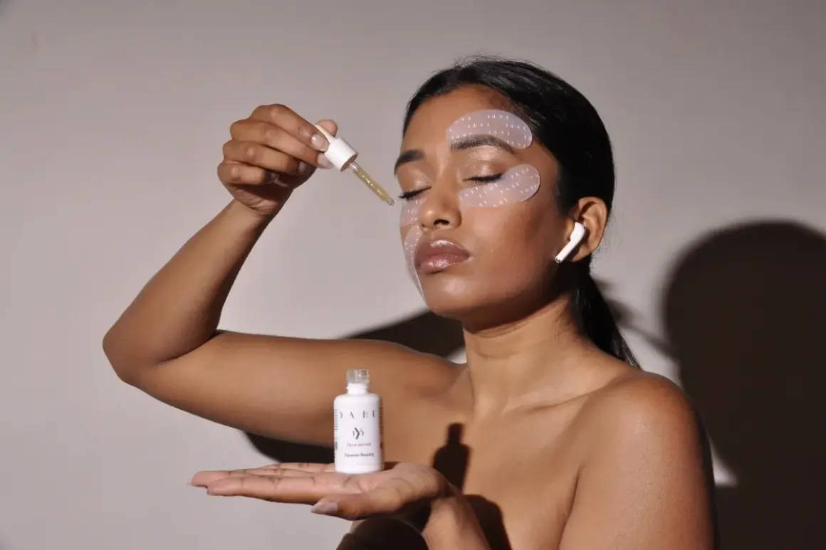 Donna applica siero per il contorno occhi disidratato. Patch idratanti e auricolari completano il rituale di bellezza.