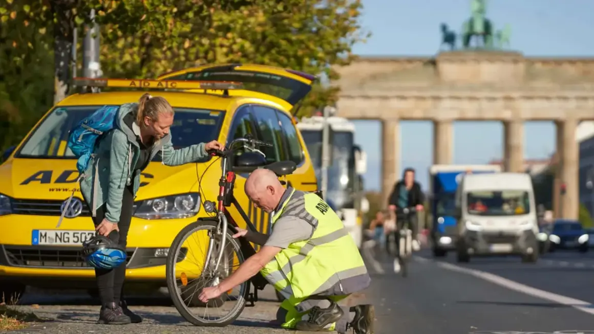 ADAC-Mitarbeiter hilft Frau bei einer **ADAC Fahrradpanne** vor dem Brandenburger Tor.