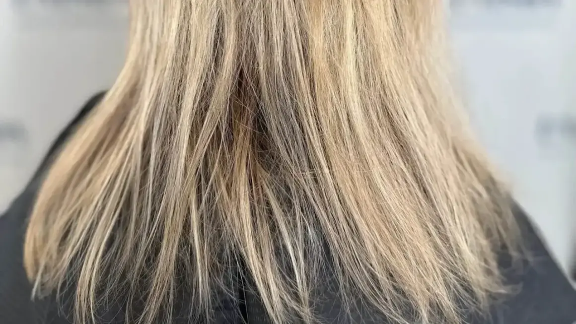 Nahaufnahme von schlecht blondierten Haaren mit ungleichmäßigen Blondtönen und sichtbaren Ansätzen.