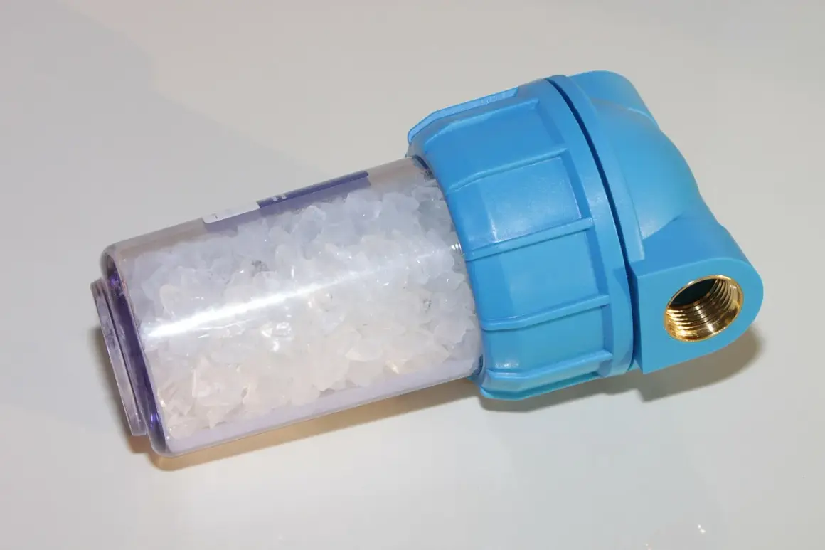 Filtre adoucisseur d'eau bleu rempli de cristaux blancs. Peut être la cause d'un problème de pression d'eau.
