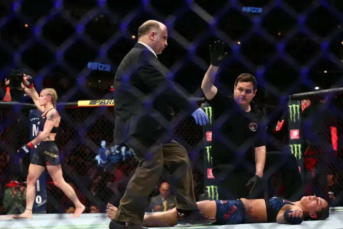 Domaren stoppar matchen. Jessica Eye ligger på mattan medan motståndaren firar.