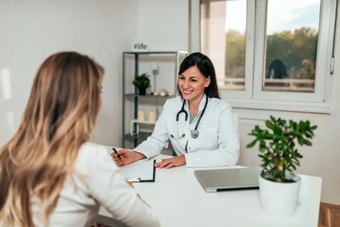 Sage-femme souriante discutant avec une patiente, évoquant une possible rééducation périnée.