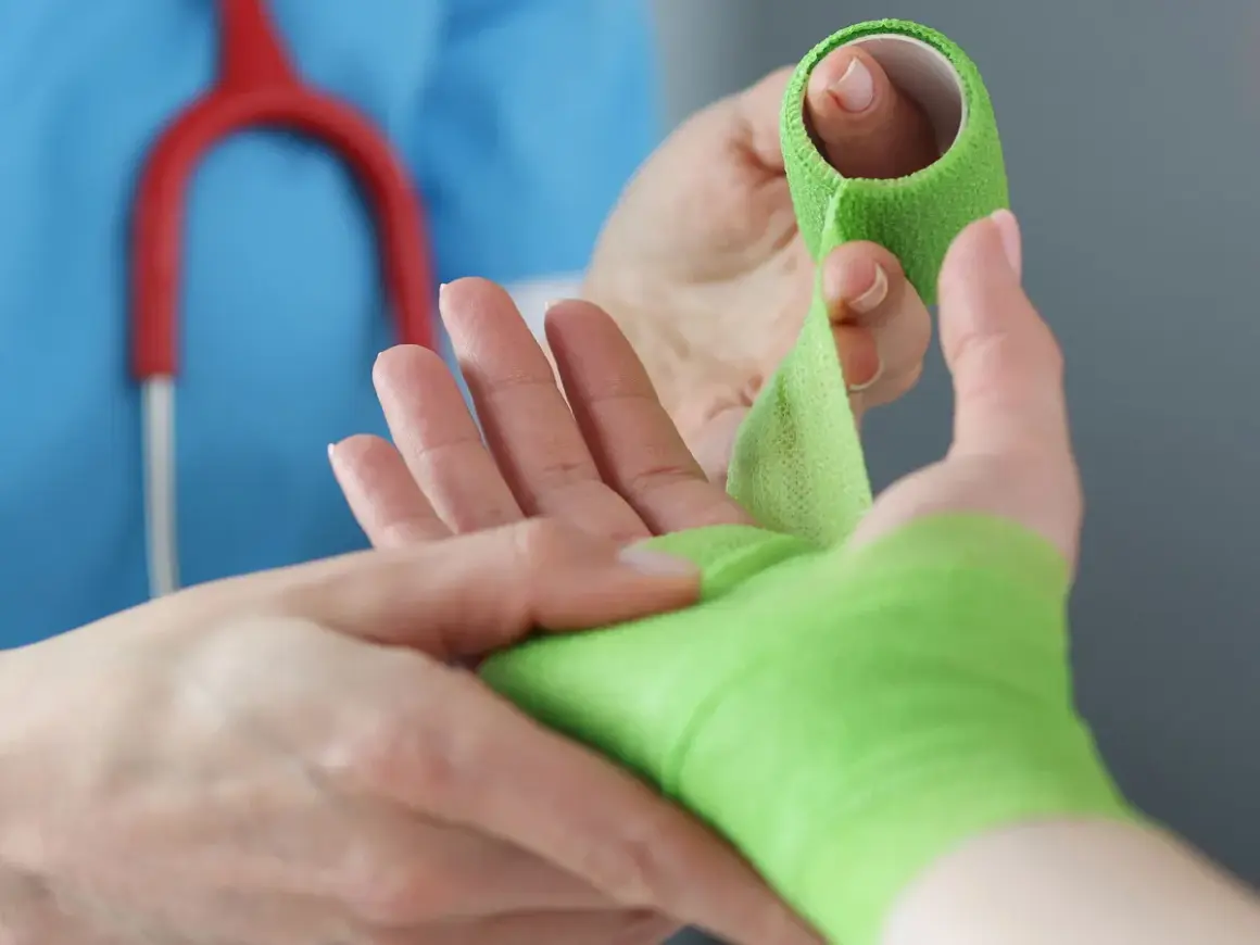 Lekarz opatruje rękę po urazie, być może po wybitym palcu. RTG potwierdzi diagnozę.