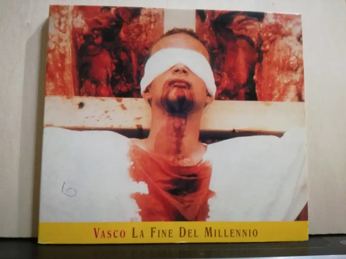 Copertina di "Vasco La Fine Del Millennio" con un uomo bendato e sanguinante, immagine disturbante che evoca la fine di un'era.