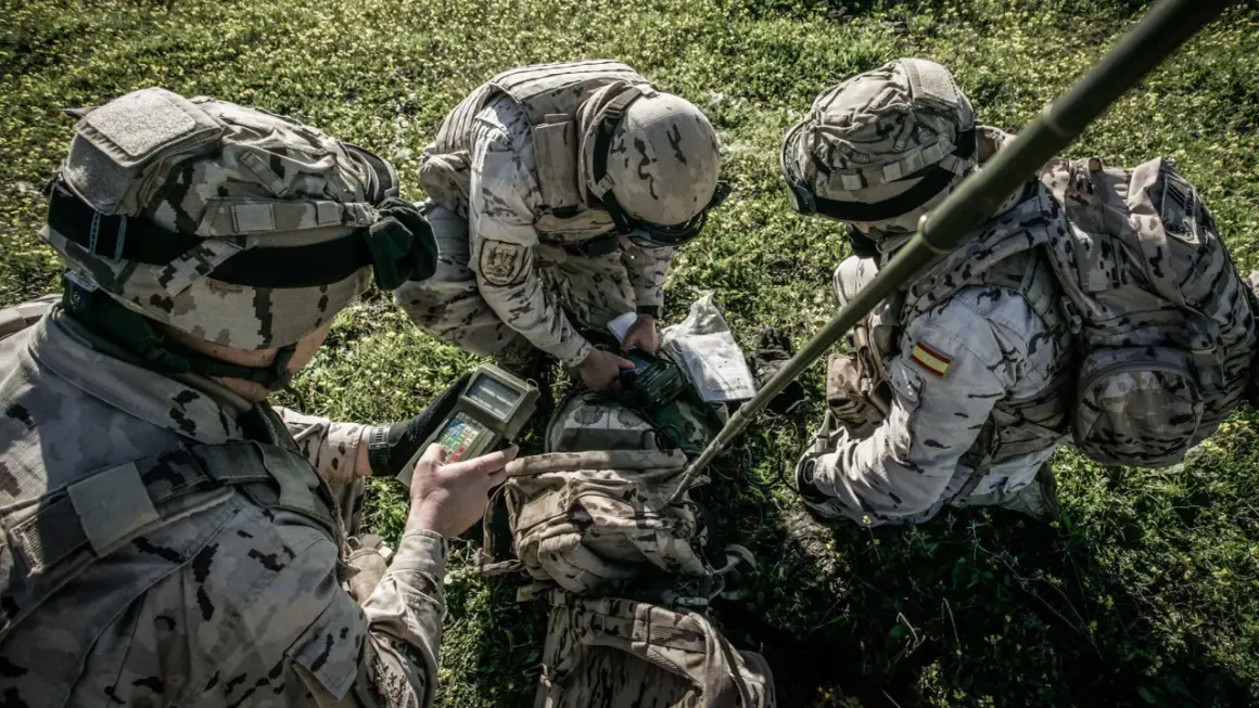 Soldados del ejército español con uniforme multicam revisan equipo en el campo.