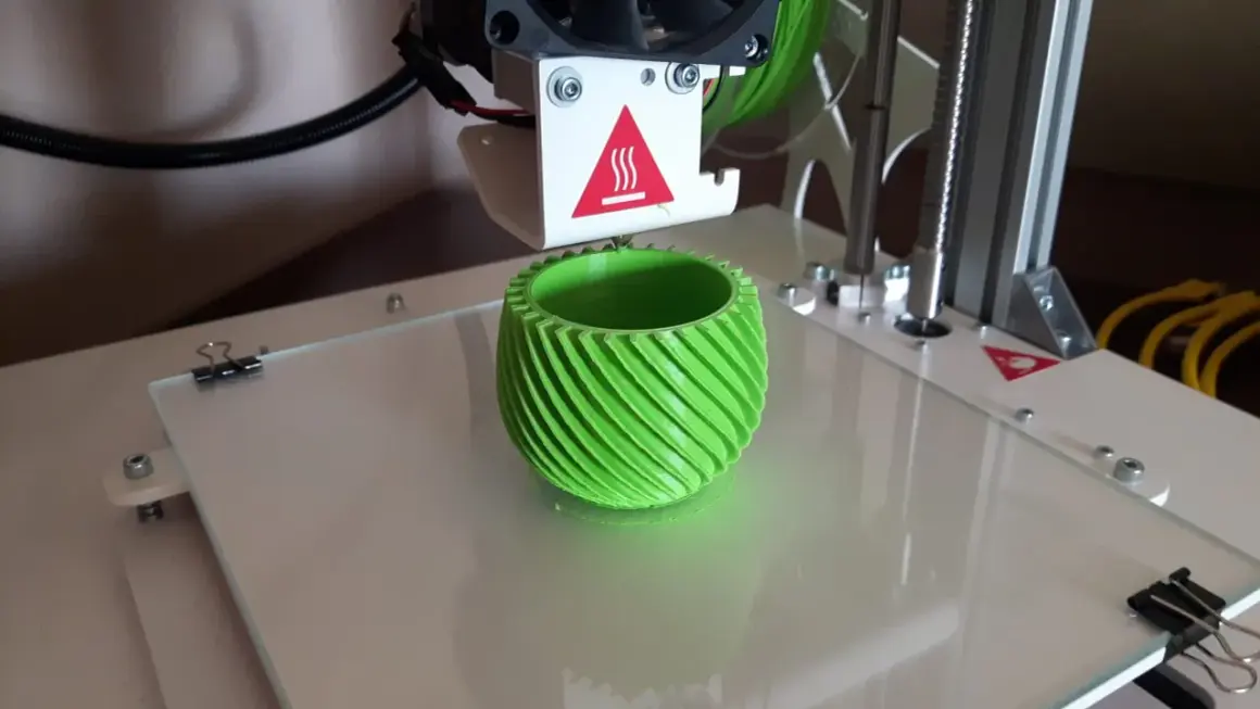 Drukarka 3D drukuje zielony, spiralny wazon.