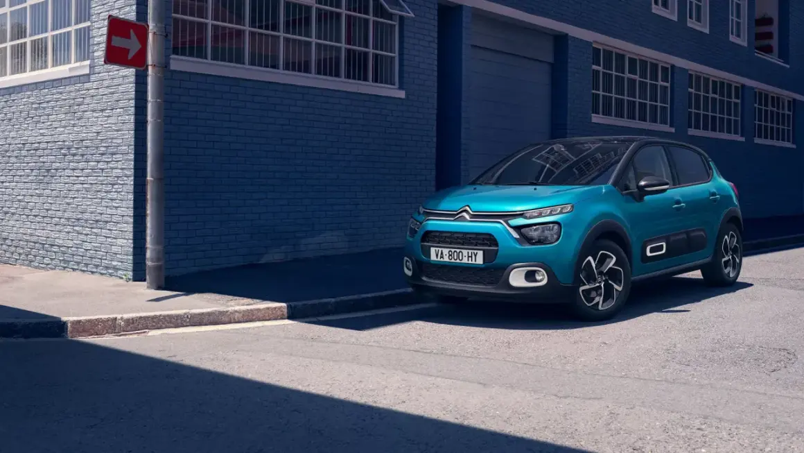 Citroën C3 bleue garée sur le trottoir, avec un panneau de signalisation. La taille pneu Citroën C3 est adaptée à ce modèle urbain.