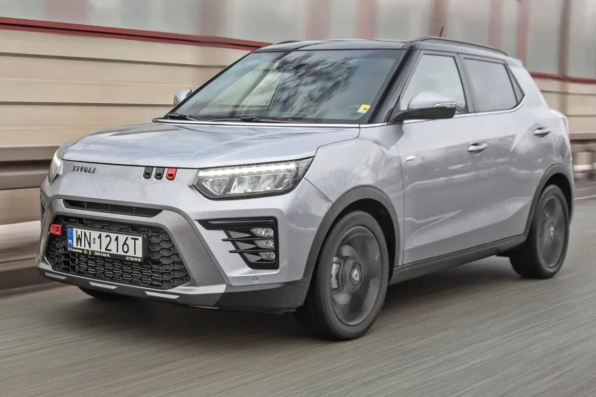 Srebrny SsangYong Tivoli z czarnym dachem pędzi po drodze.
