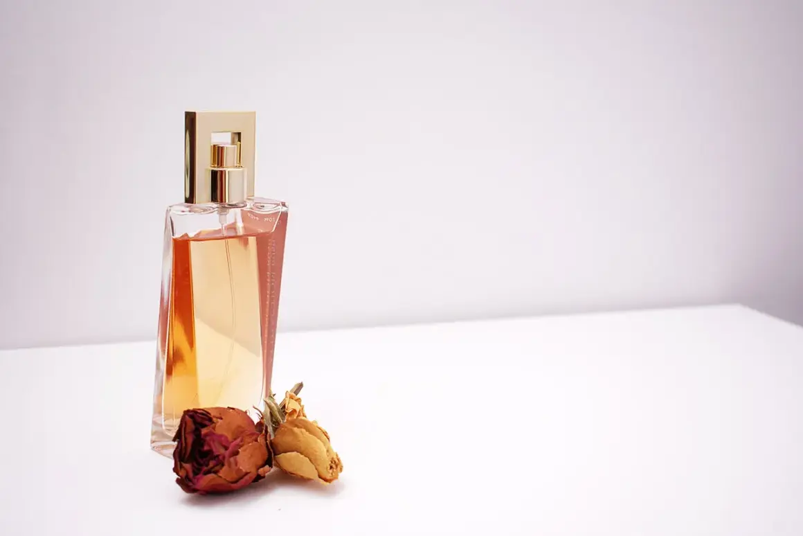 Elegancka butelka perfum z płynem w kolorze bursztynu i dwoma zasuszonymi różami. Czy tak pachnie piżmo?