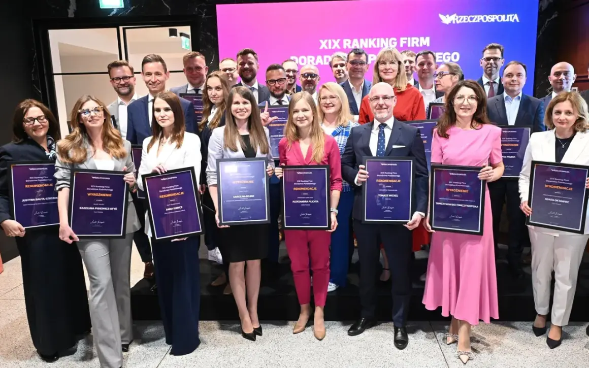 Grupa osób w eleganckich strojach pozuje z dyplomami na tle sceny z logo "Rzeczpospolita".