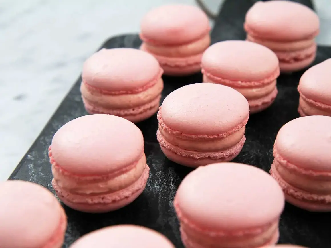 Rosa macarons på en mörk yta, perfekta för ett macarons recept.