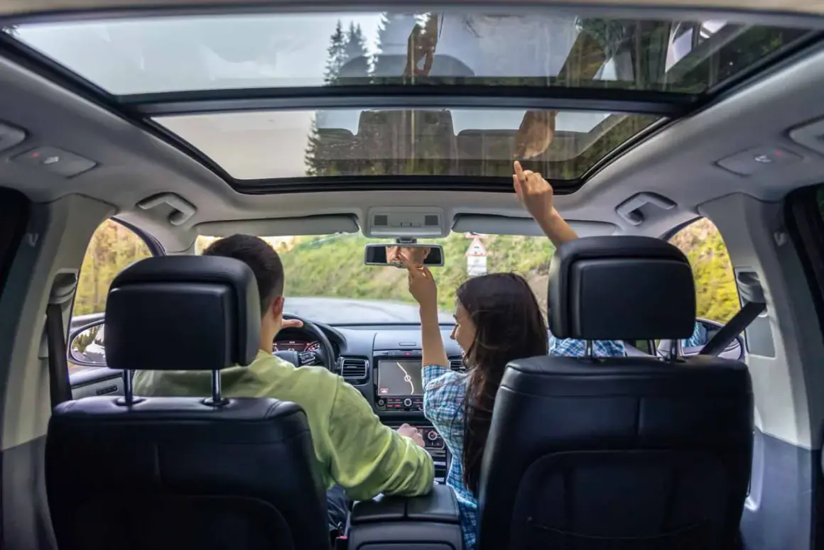 Familie im Auto mit Panoramadach. Die Sonne scheint durch das Fenster, hoffentlich kein Sonnenbrand!