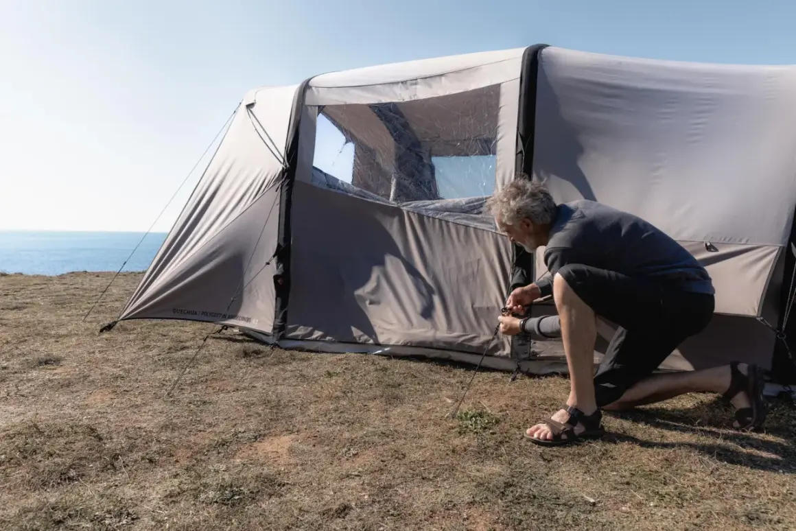 Mężczyzna rozbija namiot na trawiastym klifie nad morzem. Czy można rozbić namiot na plaży? To miejsce wygląda idealnie.