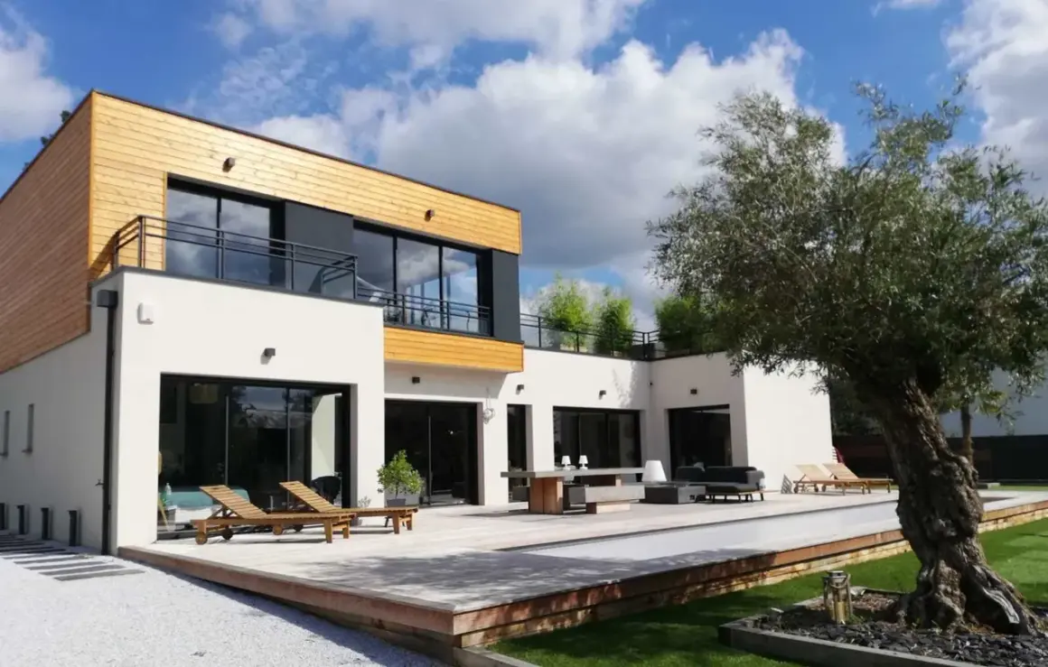 Maison moderne avec piscine et terrasse en bois. On se demande combien de m3 d'eau pour construire une maison comme celle-ci.