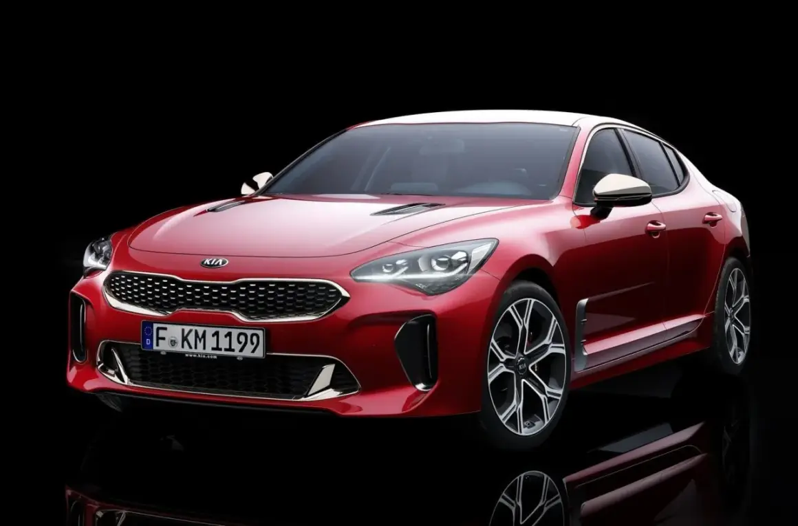 El potente motor del Kia Stinger, un sedán deportivo rojo brillante, se exhibe con su distintiva parrilla y faros LED.